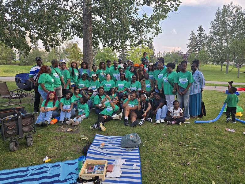 SALDAC members in green T-shirts posing together on the grass at the 2026 Picnic in the Park, with picnic blankets in front